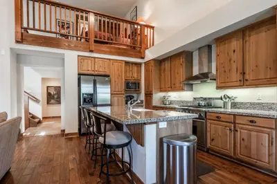 a kitchen with wooden cabinets and a large island with bar stools at Lodges 1112 - 3 Bed townhome with Loft in Mammoth Lakes
