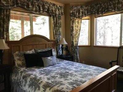 a bedroom with a bed and two windows at Large Family Home in Quiet Wooded Setting Close to Everything in Mevers