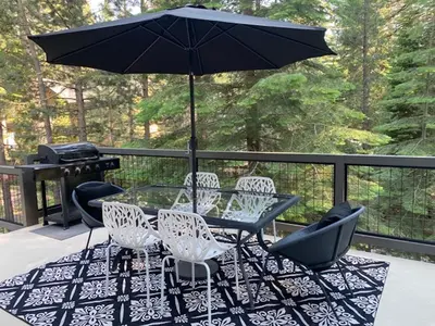 a table and chairs with an umbrella on a deck at Large Family Home in Quiet Wooded Setting Close to Everything in Mevers