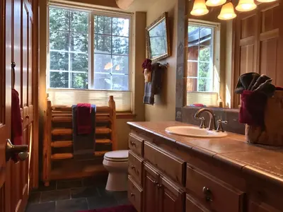 a bathroom with a sink and a toilet and windows at Large Family Home in Quiet Wooded Setting Close to Everything in Mevers
