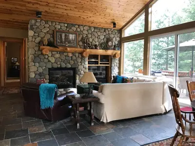 a living room with a stone wall with a fireplace at Large Family Home in Quiet Wooded Setting Close to Everything in Mevers