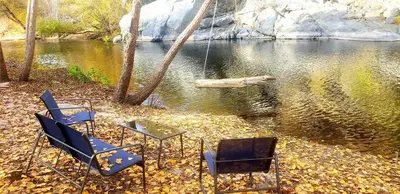 two chairs and a glass table in front of a river at Retro House on the River ! in Three Rivers