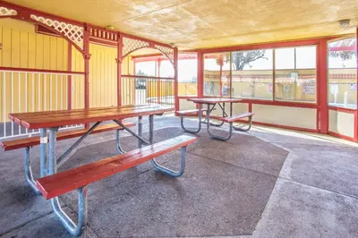 two picnic tables and benches in a room with windows at Travelodge by Wyndham Turlock in Turlock