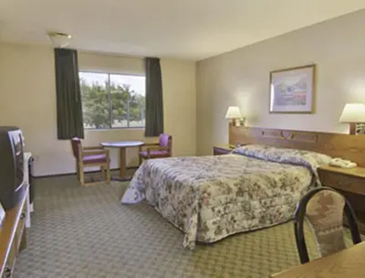 a hotel room with a bed and a table and chairs at Travelodge by Wyndham Turlock in Turlock