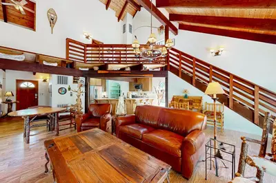 a living room with leather furniture and a table at Wishing Well Cabin in Bass Lake
