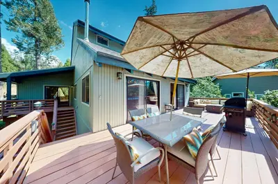 a wooden deck with a table and an umbrella at Wishing Well Cabin in Bass Lake