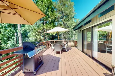 a patio with a grill and an umbrella on a deck at Wishing Well Cabin in Bass Lake