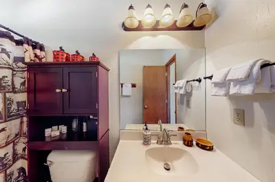 a bathroom with a sink and a toilet and a mirror at Wishing Well Cabin in Bass Lake