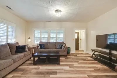 a living room with two couches and a flat screen tv at Sunny Turlock Cottage Walk to Downtown! in Turlock