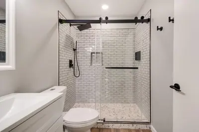 a white bathroom with a shower and a toilet at Waterfront Mariposa Hideaway Hot Tub and Mtn Views! in Mariposa