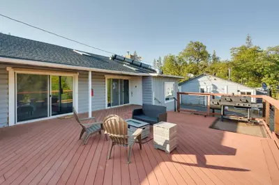 a deck with two chairs and a grill on a house at Waterfront Mariposa Vacation Rental with Hot Tub in Mariposa