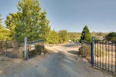 a gate on a dirt road next to a field at Waterfront Mariposa Vacation Rental with Hot Tub in Mariposa