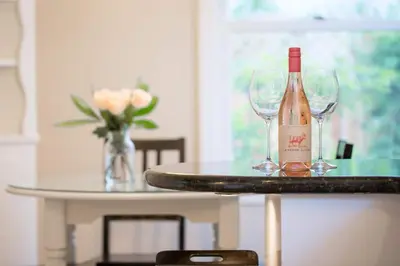 a bottle of wine sitting on a table with two wine glasses at Oasis East Sac Charming Home with Saltwater Pool and Casita in Sacramento