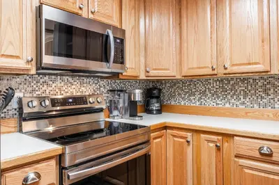 a kitchen with wooden cabinets and a stove and microwave at Summit Forester #47 BLDG.2 Bedrm / 2 bath Ski in Ski Out! Steps to Chair 15 at Little Eagle Lodge! in Mammoth Lakes