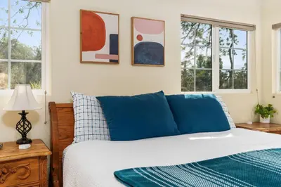 a bedroom with a bed with blue pillows and windows at Views, Hot Tub, Outdoor Shower, 15m from Sequoia in Three Rivers