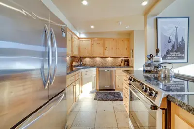 a kitchen with wooden cabinets and a stainless steel refrigerator at Mammoth Lakes Condo - Steps to Ski Lift! in Mammoth Lakes