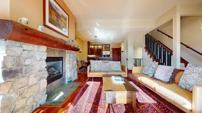 a living room with a couch and a stone fireplace at Juniper Crest #2 townhouse in Mammoth Lakes