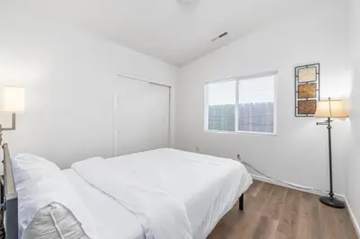 a white bedroom with a bed and a window at 3BR Cozy Home~ Stylish & New ~ UC Merced ~ en route Yosemite! in Merced