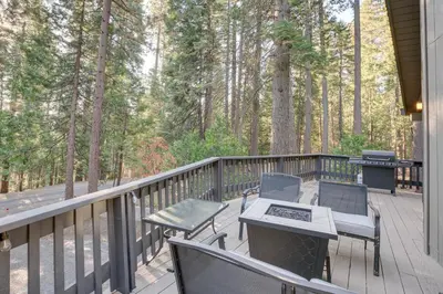 a porch with chairs and a grill on a deck with trees at Arnold Cabin Near Calaveras Big Trees State Park! in Arnold