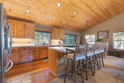 a kitchen with wooden cabinets and a kitchen island with bar stools at Alpen Glow by Tahoe Getaways - Private Hot Tub, Close to Northstar in Carnelian Bay