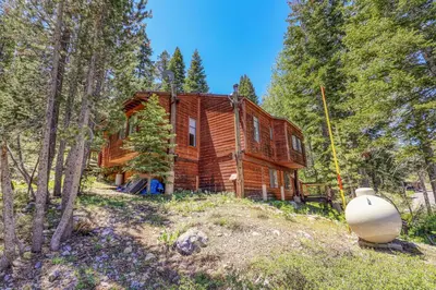 a log cabin in the woods with a white object in front of it at Alpine Escape by Tahoe Getaways - Shuttle to Ski Slopes & Fireplace in Alpine Meadows