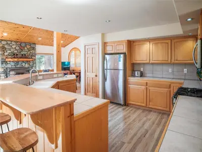 a kitchen with wooden cabinets and a stainless steel refrigerator at Bear Peak Cabin by Tahoe Getaways - Tahoe Donner Rental with Private Hot Tub and Bonus Room in Truckee