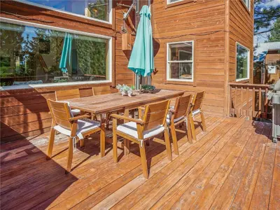 a wooden table with chairs and an umbrella on a deck at Bear Peak Cabin by Tahoe Getaways - Tahoe Donner Rental with Private Hot Tub and Bonus Room in Truckee