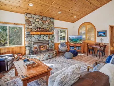 a living room with a stone fireplace and a table at Bear Peak Cabin by Tahoe Getaways - Tahoe Donner Rental with Private Hot Tub and Bonus Room in Truckee