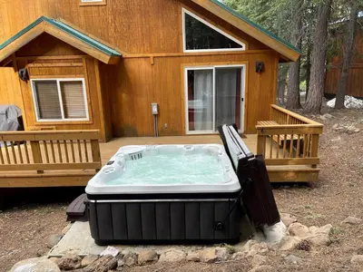 a large hot tub sitting in front of a cabin at Bear's Lair by Tahoe Getaways - 3 BR in Tahoe Donner with Hot Tub & Bonus Room! in Truckee