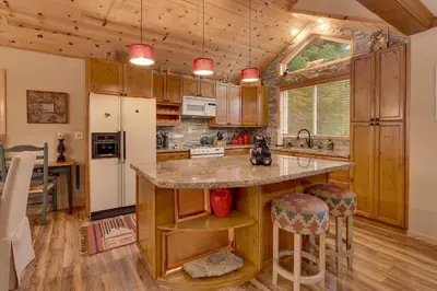 a kitchen with wooden cabinets and a kitchen island with bar stools at Bear's Lair by Tahoe Getaways - 3 BR in Tahoe Donner with Hot Tub & Bonus Room! in Truckee