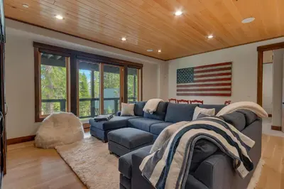 a living room with a couch and an american flag on the wall at Bluebird Lodge by Tahoe Getaways - 4 BR with Hot Tub, Pool Table & Lake Views in Carnelian Bay