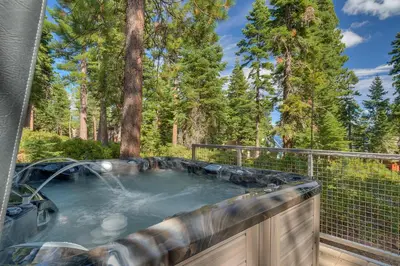 a hot tub on a deck with trees at Bluebird Lodge by Tahoe Getaways - 4 BR with Hot Tub, Pool Table & Lake Views in Carnelian Bay