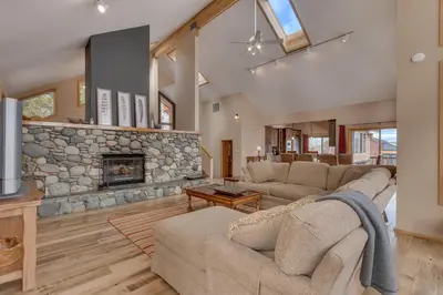 a living room with couches and a stone fireplace at Bitter Brush by Tahoe Getaways -4 BR Pet Friendly, Northstar Home with Hot Tub, Pool Table, & Ski Shuttle in Truckee