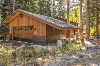 a wooden cabin in the woods with trees at Birchwood Retreat by Tahoe Getaways - Newly Remodeled Pet Friendly Home in Alpine Meadows with Wood Fireplace, Hot Tub & Ski Shuttle! in Alpine Meadows