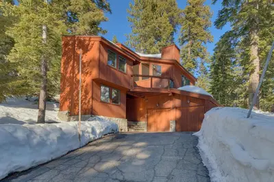 a home in the woods with snow around it at Big John at Alpine Meadows by Tahoe Getaways - Mountain Views, Cozy Fireplace, Shuttle to Slopes! in Alpine Meadows
