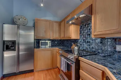 a kitchen with wooden cabinets and a stainless steel refrigerator at Big John at Alpine Meadows by Tahoe Getaways - Mountain Views, Cozy Fireplace, Shuttle to Slopes! in Alpine Meadows