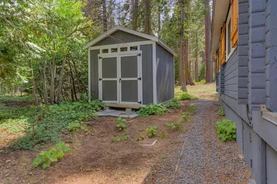 a small gray shed next to a house at Blackwood Bungalow on the West Shore by Tahoe Getaways - 3 BR Pet Friendly & Walking Distance to the Lake in Homewood