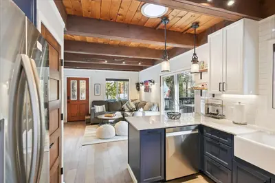 a kitchen with white cabinets and a living room at Cobalt Cabin by Tahoe Getaways - Beautifully Remodeled Pet Friendly 3 BR with Hot Tub & EV in Carnelian Bay