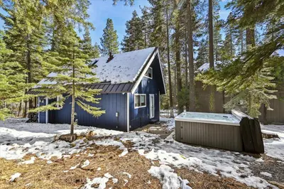 a blue house with a hot tub in the snow at Cobalt Cabin by Tahoe Getaways - Beautifully Remodeled Pet Friendly 3 BR with Hot Tub & EV in Carnelian Bay