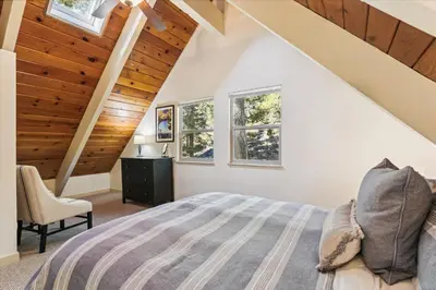 a bedroom with a bed and two windows at Cedar Chalet by Tahoe Getaways - Stunning 3BR with Fireplace & Pet Friendly in Tahoe Vista