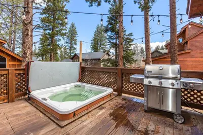 a hot tub on a deck with a stove at Cedar Crest at Winter Creek by Tahoe Getaways - 3BR, Walk to Ice Skating, Near Downtown and Northstar with Private Hot Tub! in Truckee