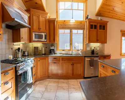 a kitchen with wooden cabinets and a stove top oven at Coyote Run Retreat by Tahoe Getaways - 3BR Pet Friendly with HOA Amenities, Minutes to Downtown Truckee & Northstar Resort! in Truckee
