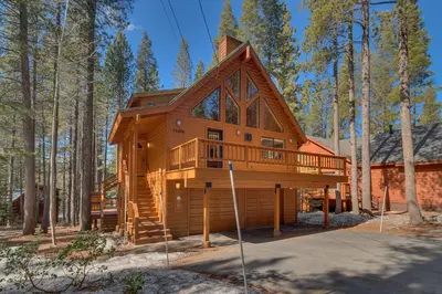 a cabin in the woods with a wrap around deck at Cottonwood by Tahoe Getaways - 3BR Tahoe Donner with 2 Bonus Rooms, Hot Tub, Fireplace, Ping Pong & HOA Amenities in Truckee