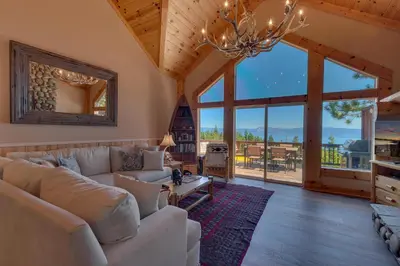 a living room with a couch and large windows at Crystal Lakeview Lodge by Tahoe Getaways - Private Hot Tub, Foosball Table & Tahoe Park HOA in Tahoe City
