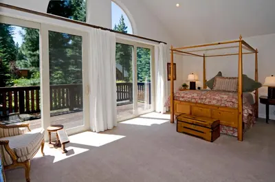 a bedroom with a canopy bed and large windows at Big Springs by Tahoe Getaways - 6BR w Ski Shuttle, Fireplace & Entertainment Room in Truckee
