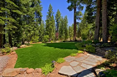 a garden with green grass and a stone pathway at Big Springs by Tahoe Getaways - 6BR w Ski Shuttle, Fireplace & Entertainment Room in Truckee
