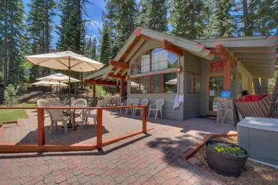 a patio with a table and chairs and an umbrella at Big Springs by Tahoe Getaways - 6BR w Ski Shuttle, Fireplace & Entertainment Room in Truckee