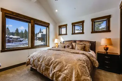 a bedroom with a large bed and two windows at Allure at Schaffer's Mill by Tahoe Getaways - 4BR Pet-Friendly Home w Private Hot Tub & Air Conditioning! in Truckee