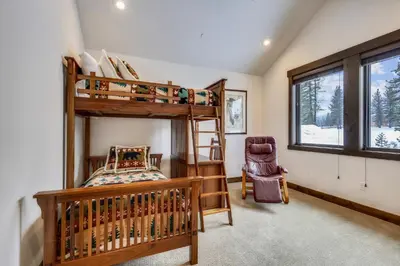 a bedroom with two bunk beds and a chair at Allure at Schaffer's Mill by Tahoe Getaways - 4BR Pet-Friendly Home w Private Hot Tub & Air Conditioning! in Truckee