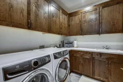 a washing machine in a kitchen with wooden cabinets at Allure at Schaffer's Mill by Tahoe Getaways - 4BR Pet-Friendly Home w Private Hot Tub & Air Conditioning! in Truckee